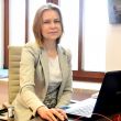 Zdjęcie portretowe: dr inż. Edyta Marcinkiewicz siedzi w gabinecie przy biurku i otwartym laptopie.