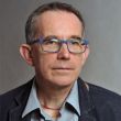 Zdjęcie portretowe: prof. Michał Strzelecki w ciemnej marynarce i szarej koszuli na szarym tle.