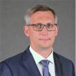 Zdjęcie portretowe: prof. Łukasz Albrecht, prorektor ds. nauki Politechniki Łódzkiej, w granatowym garniturze na szarym tle.