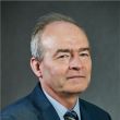 Portrait photo: Prof. Dariusz Gawin, Assoc. Prof. Eng, in a dark suit, a blue shirt and a tie  against a grey background.