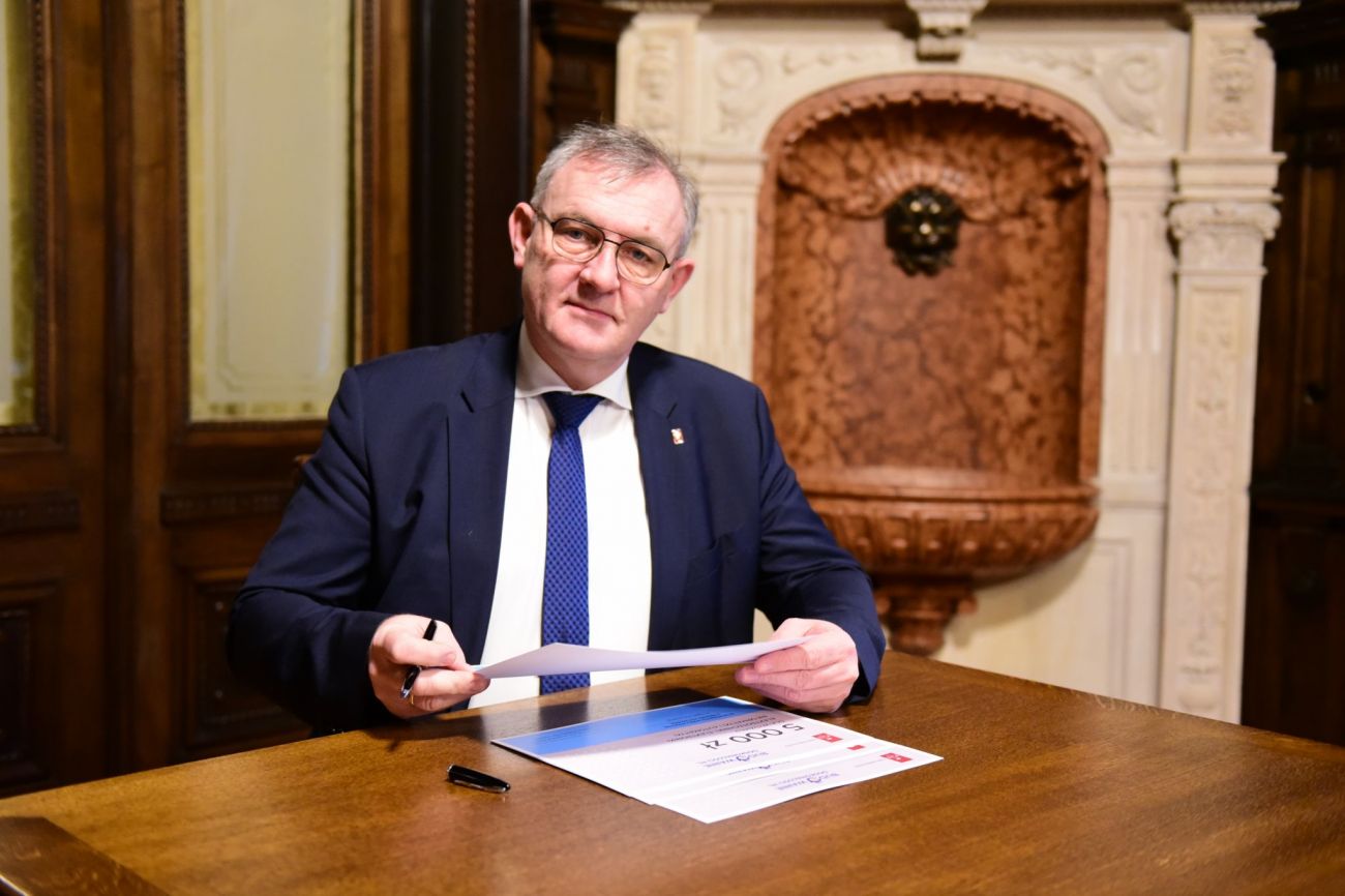Prof. Krzysztof Jóźwik, rektor PŁ, siedzi przy biurku w swoim gabinecie i podpisuje dokumenty.