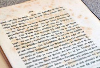 Photograph of a white page with black gothic text.