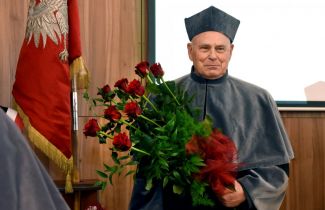 prof. Peter Hagedorn w todze i bukietem róż podczas uroczystości wręczenia tytułu DHC Politechniki Łódzkiej.