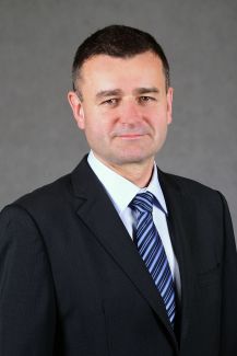 Zdjęcie portretowe: prof. Andrzej Romanowski, prorektor ds. kształcenia Politechniki Łódzkiej, w czarnym garniturze na szarym tle.