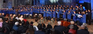 Członkowie Akademickiego Chór Politechniki Łódzkiej w niebieskich strojach podczas koncertu w dużej hali.