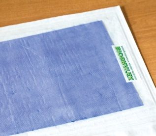 Fragment of a flat white package with visible biodegradable purple material.