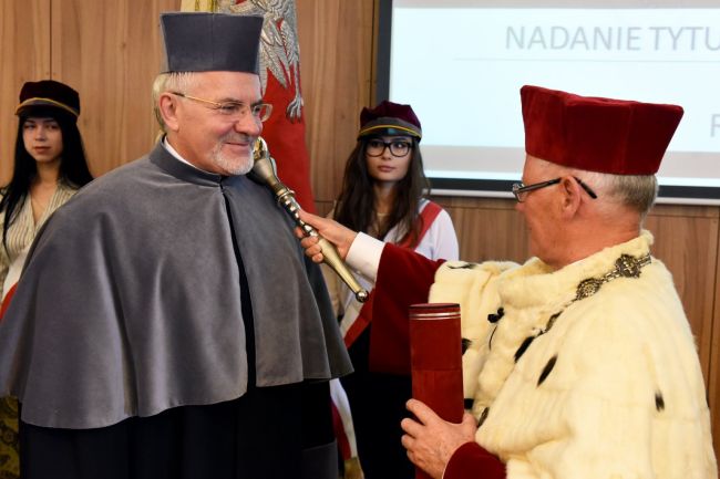 Prof. Sławomir Wiak w rektorskiej todze nadaje tytuł Doktora Honoris Causa prof. Wiktorowi Weberowi, który stoi w szarej todze po lewej stronie.