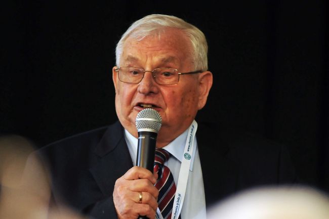 Prof. Tadeusz Paryjczak w garniturze mówi do mikrofonu.