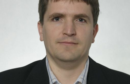Zdjęcie portretowe: dr inż. Łukasz Frącczak w ciemnej marynarce na białym tle.