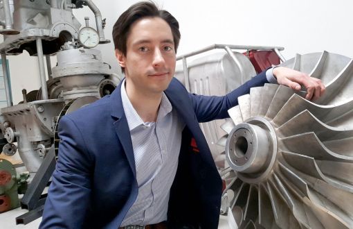 Portrait photo: Dr Eng Grzegorz Liśkiewicz in his jacket is standing next to a grey construction element.