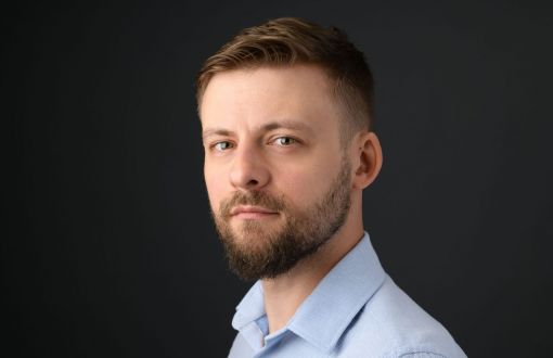 Zdjęcie portretowe dr Krzysztof Chyliński w niebieskiej koszuli na ciemnoszarym tle.