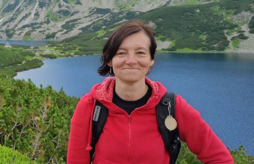 prof. Mariola Buczkowska w czerwonym polarze. W tle jezioro i góry - Tatry.