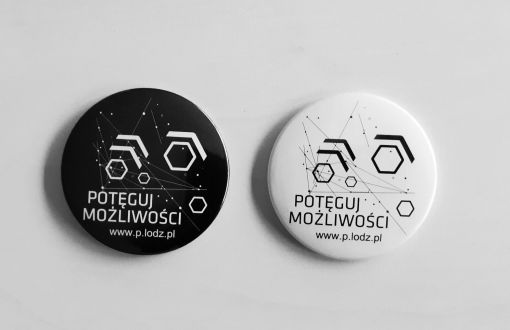 Dwa okrągłe magnesy (biały i czarny) z abstrakcyjną grafiką i hasłem Potęguj możliwości.