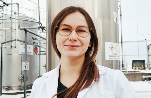 Zdjęcie portretowe: Patrycja Trajdos w białym fartuchu. W tle specjalistyczna aparatura.