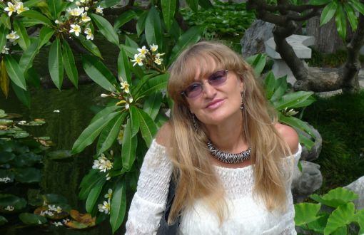 Zdjęcie portretowe: prof. Urszula Ledzewicz w białej bluzce na tle zieleni.