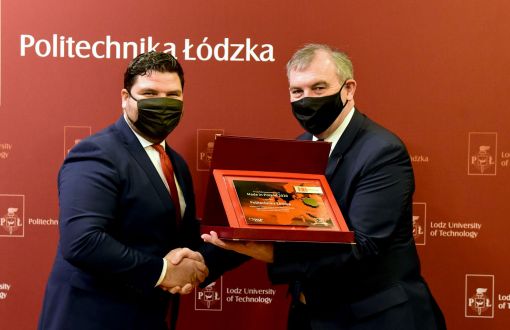 Rektor prof. Krzysztof Jóźwi0k odbiera gratulacje od prezesa Polskiej Agencji Przedsiębiorczości Wojciecha Pomarańskiego. Uścisk dłoni. JM Rektor trzyma pamiątkową tabliczkę w bordowym etui.