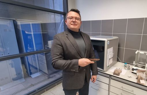 Dr inż. Adam Szufa w garniturze przy stanowisku laboratoryjnym.