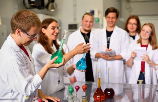 Studenci PŁ w białych fartuchach w pracowni chemicznej.
