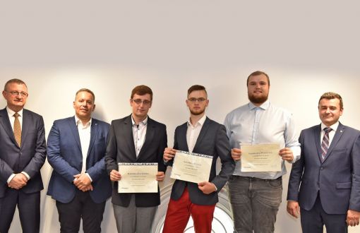 Trzej studenci prezentują dyplomy kwalifikujące do programu oraz prorektor PŁ, dziekan WEEIA i dyrektor zakładu Whirpool.