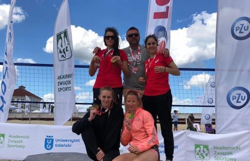Reprezentantki PŁ z trenerem Tomaszem Gapińskim na plaży prezentują medale.