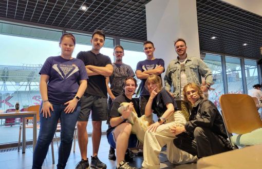 ośmioro młodych ludzi pozuje do zdjęcia wewnątrz sali konferencyjnej